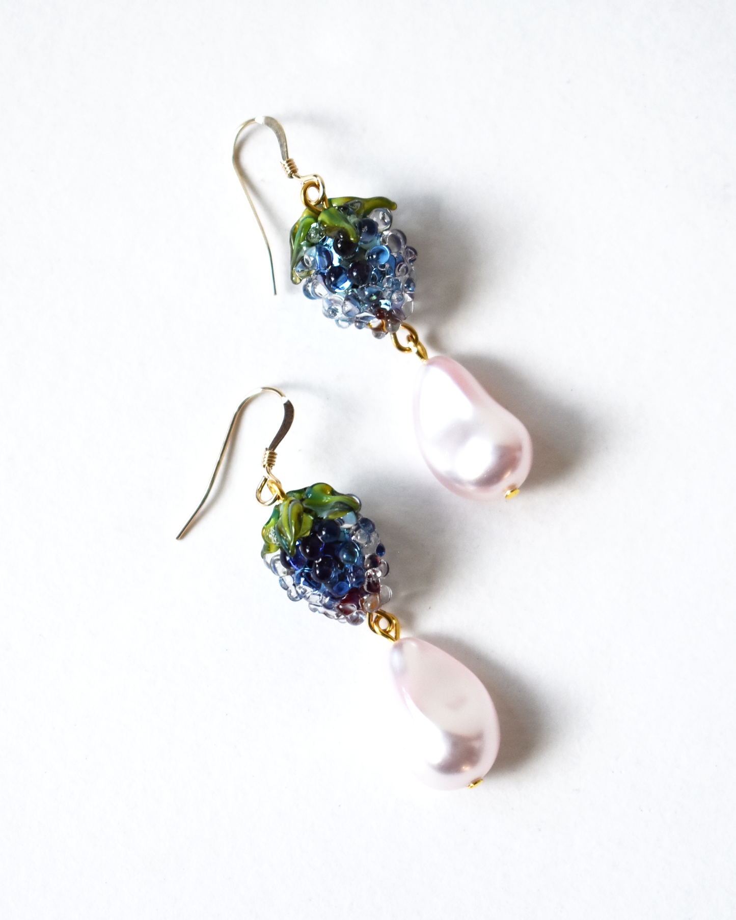 Pair of earrings with colorful beads and a pink pearl on a white background
