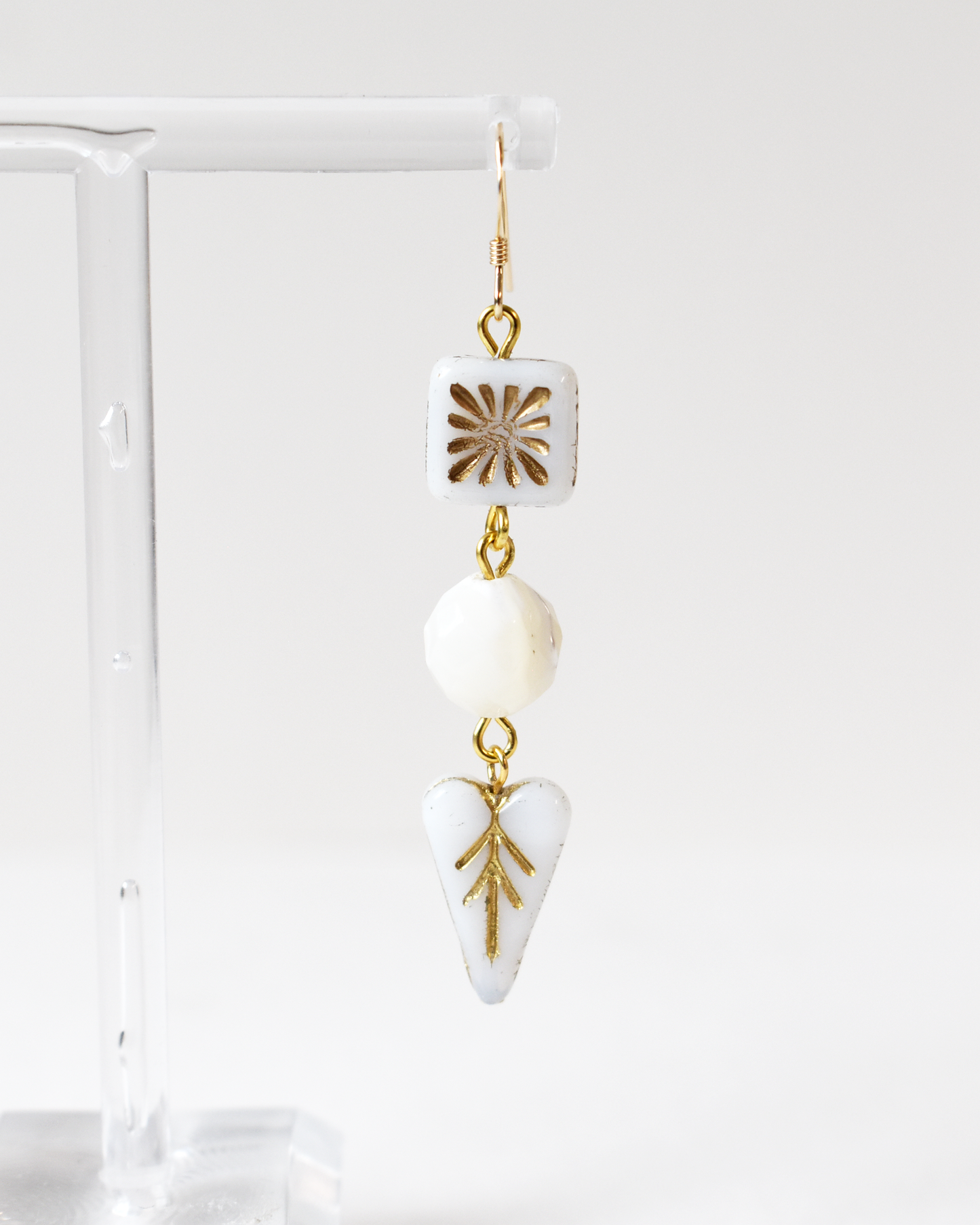 Earrings with gold and white geometric designs on a white background