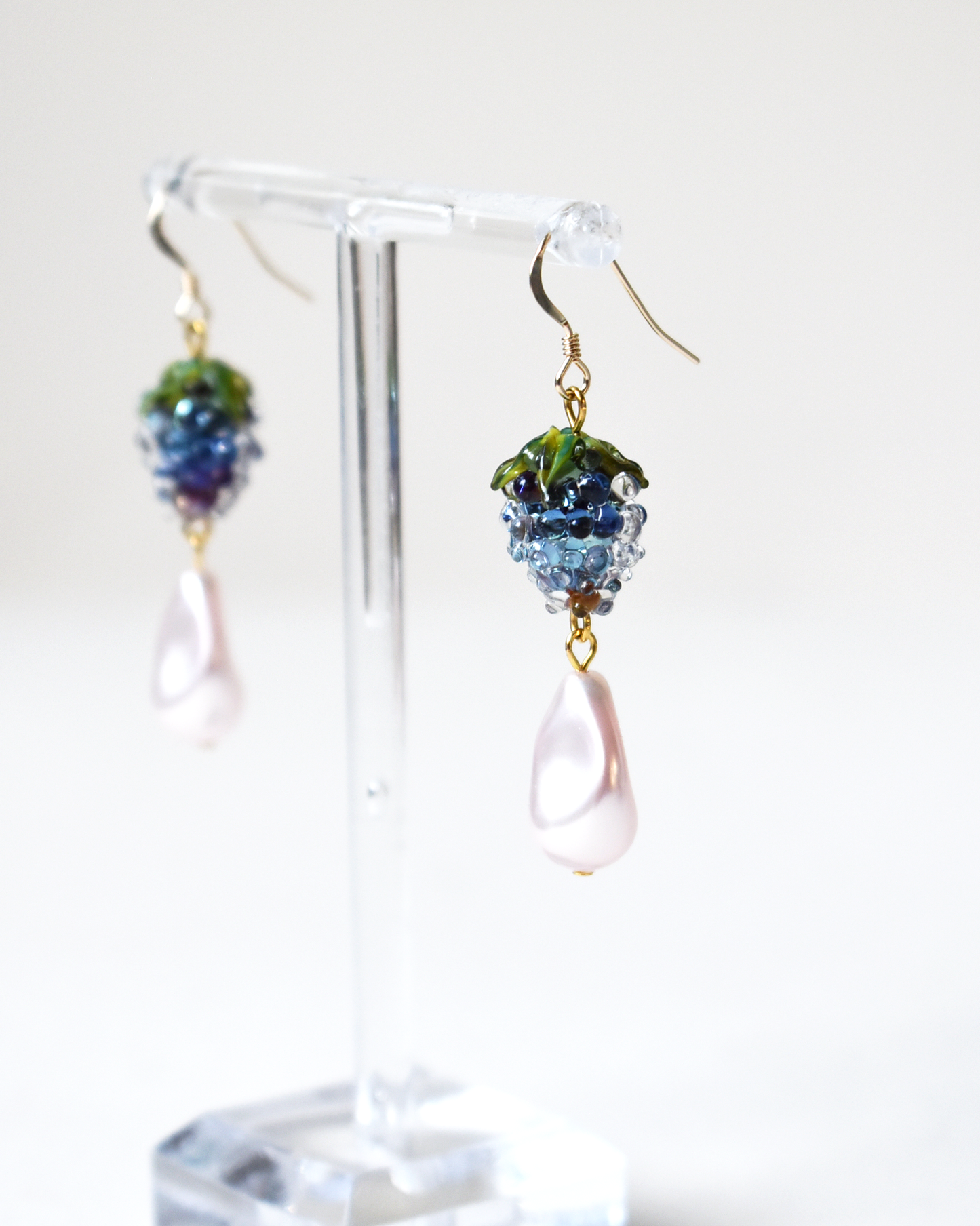 Pair of earrings on a clear stand with a white background