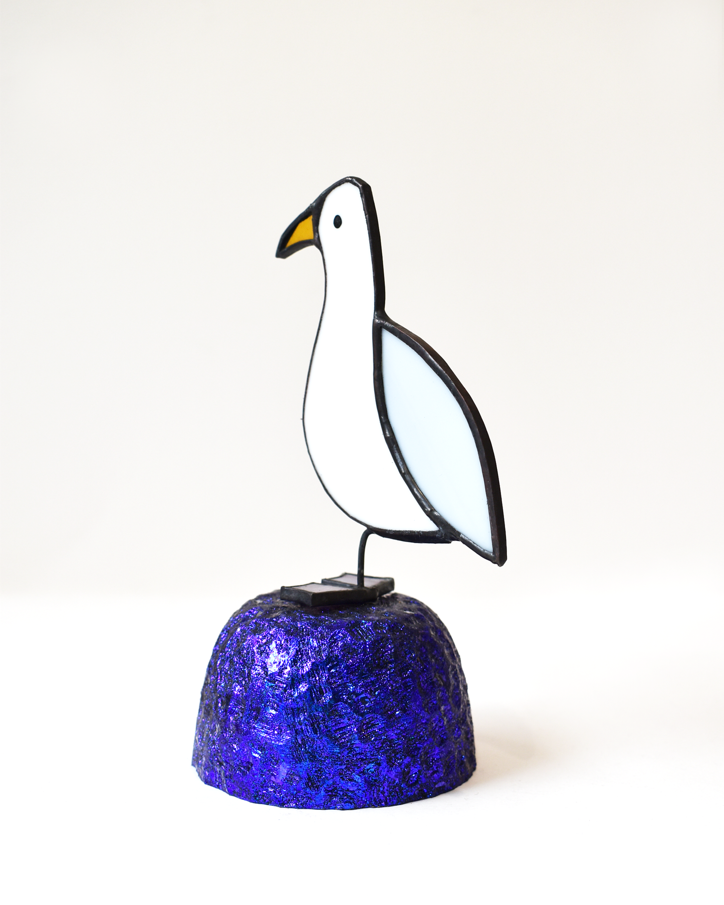 Decorative glass seagull on a blue base against a white background