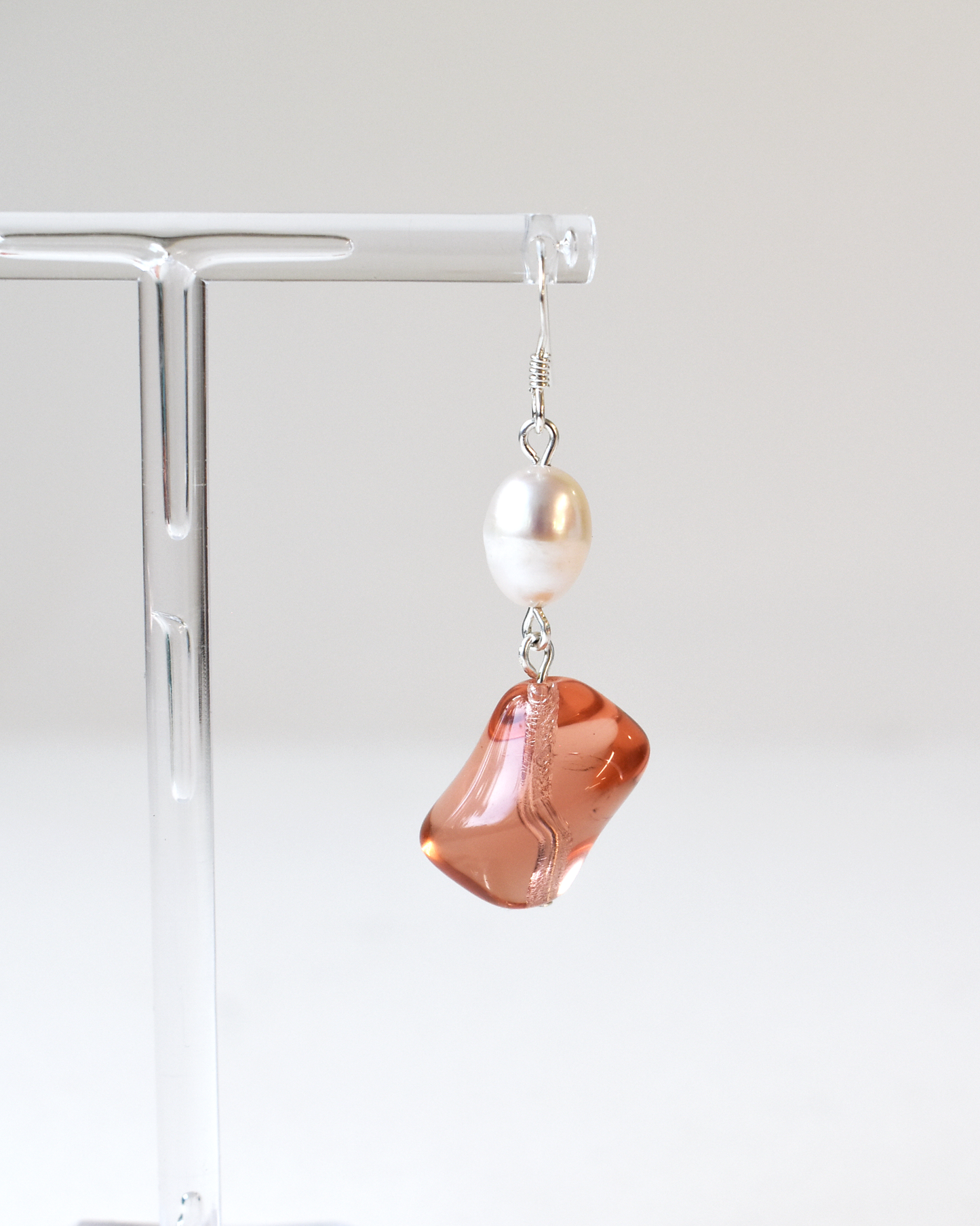 Earring with a large pink stone and pearl on a white background