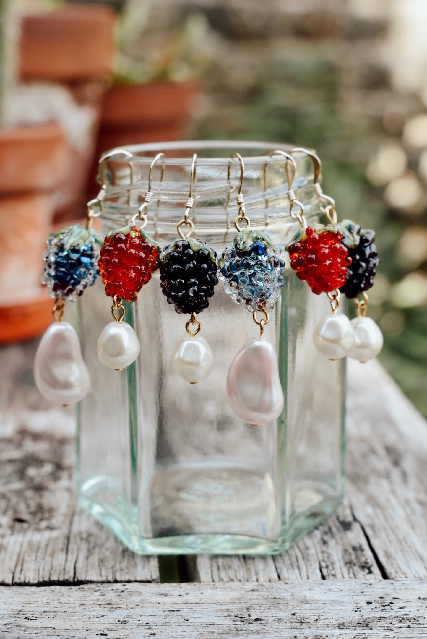 Jewelry set with colorful beads and pearls displayed in a glass jar on a wooden surface.