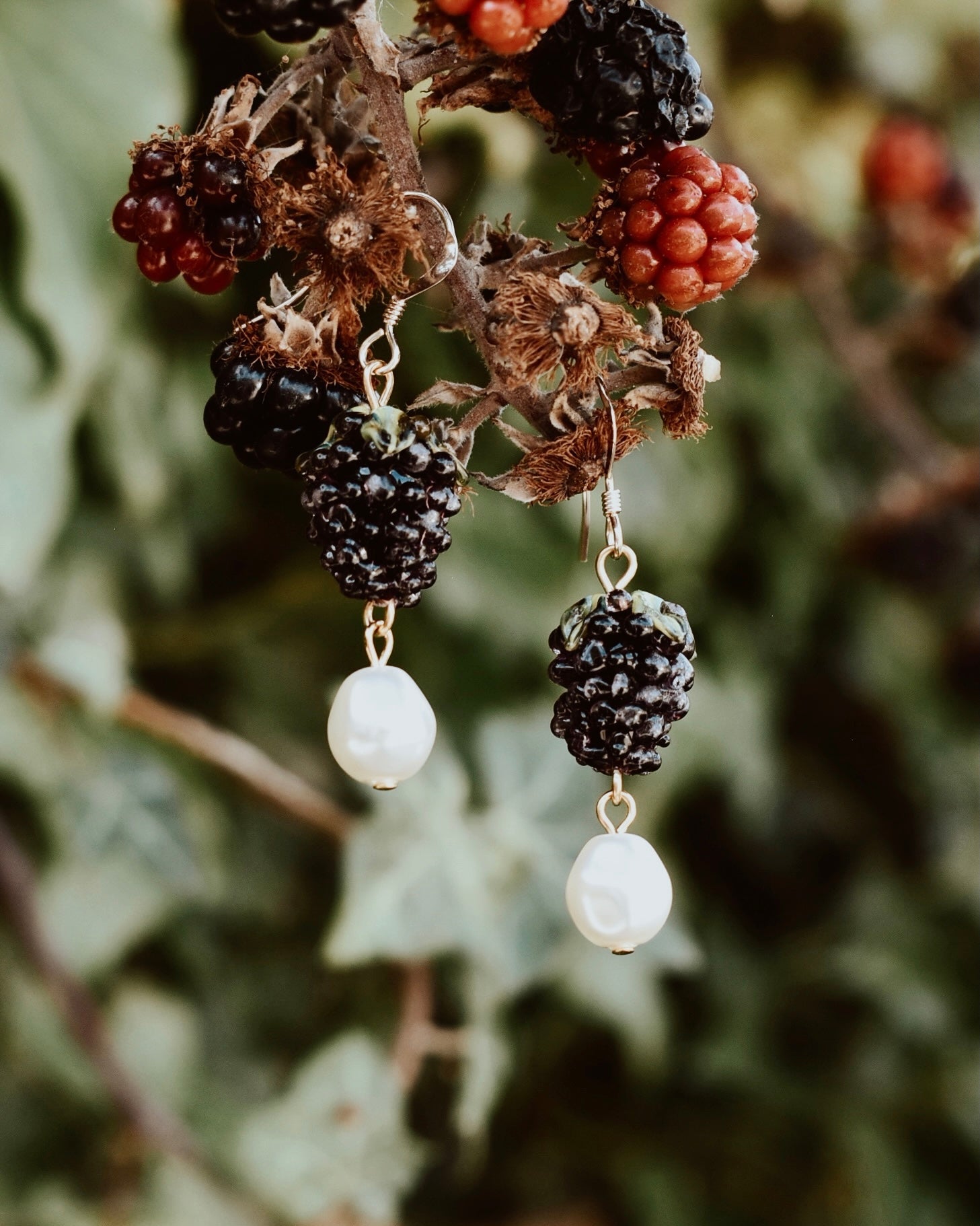 Earrings with black and white beads hanging from a branch with berries.