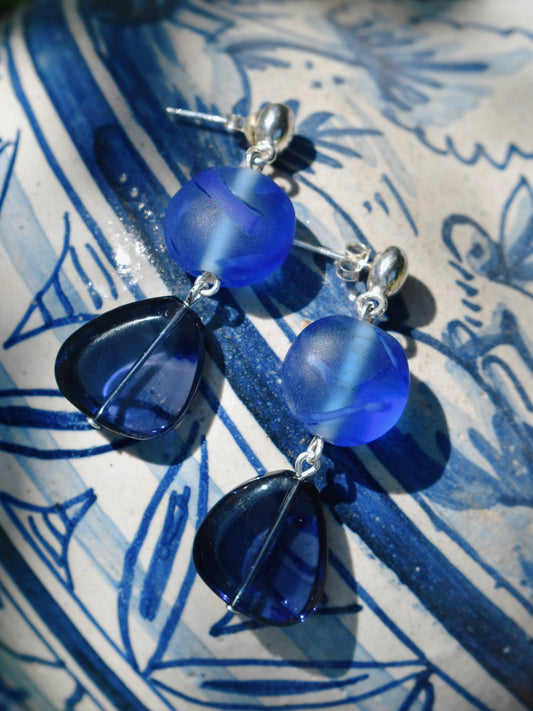 Blue glass bead earrings on a blue and white patterned surface