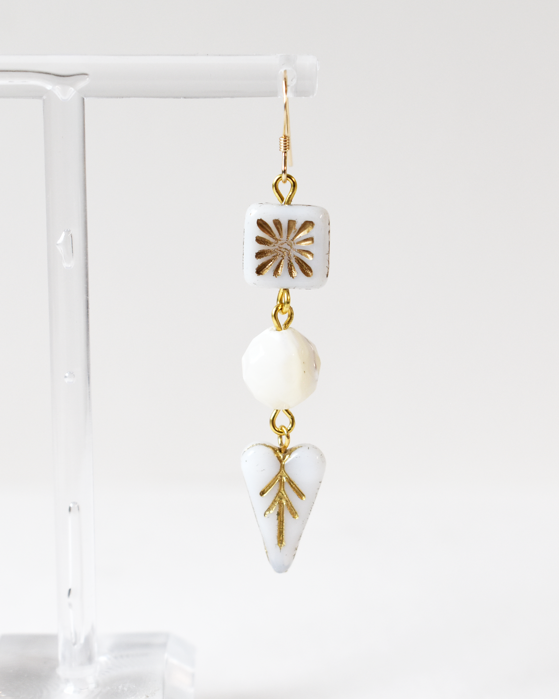 Earrings with gold and white geometric designs on a white background