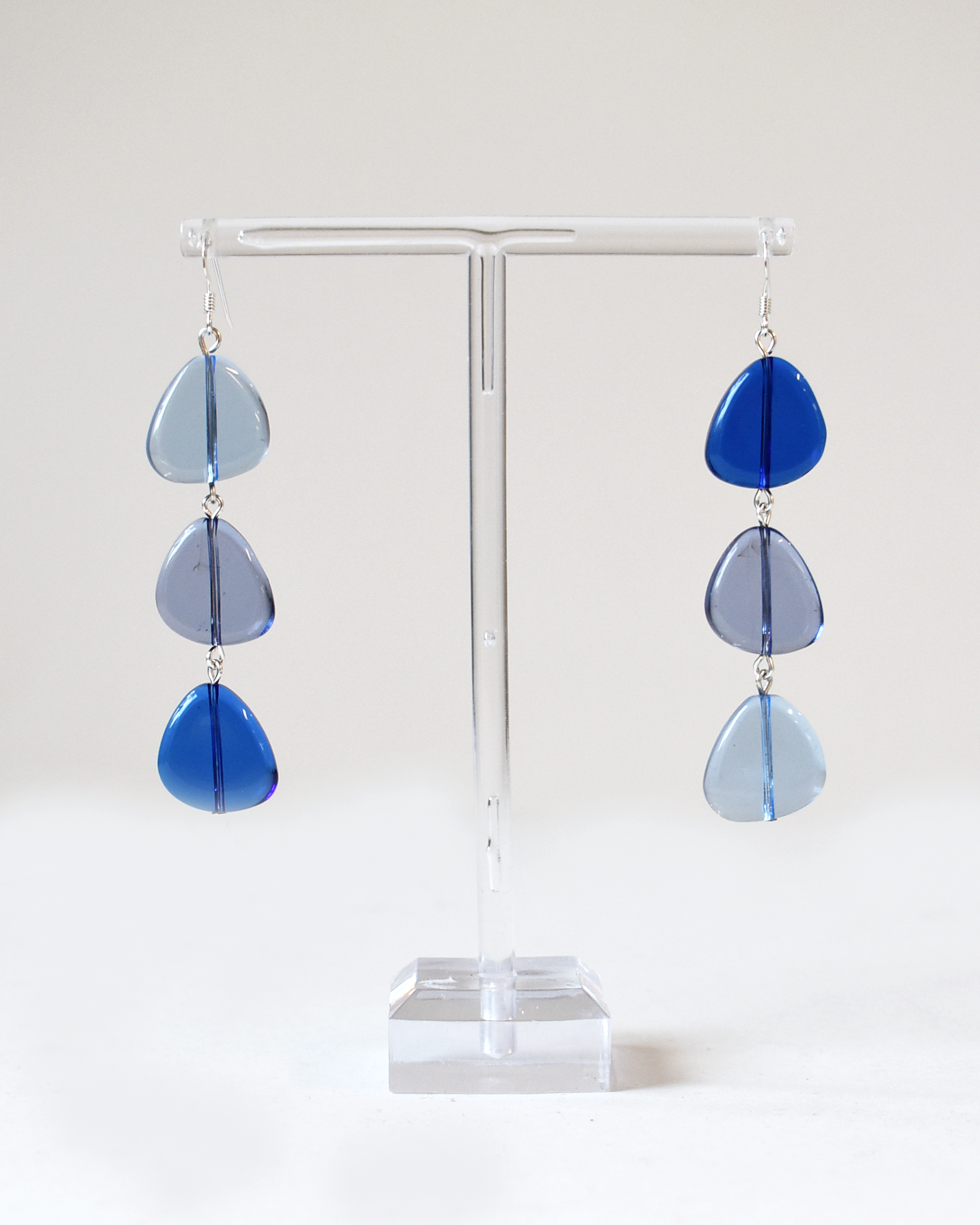 Blue teardrop earrings on a white stand with a white background