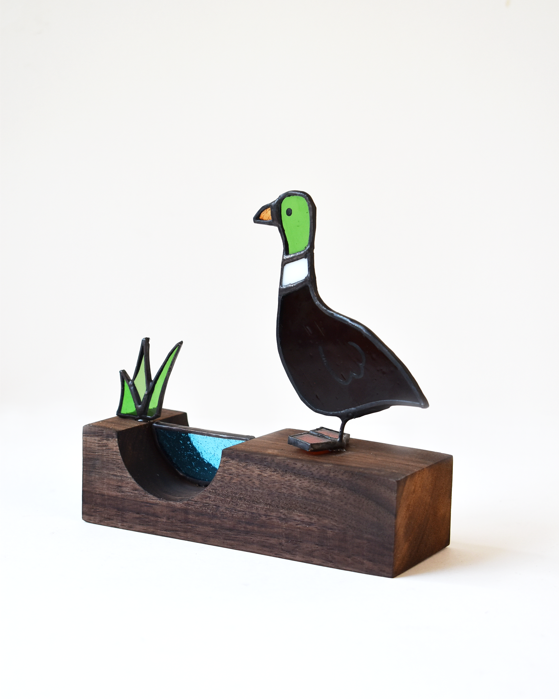 Decorative duck sculpture on a wooden base with a white background