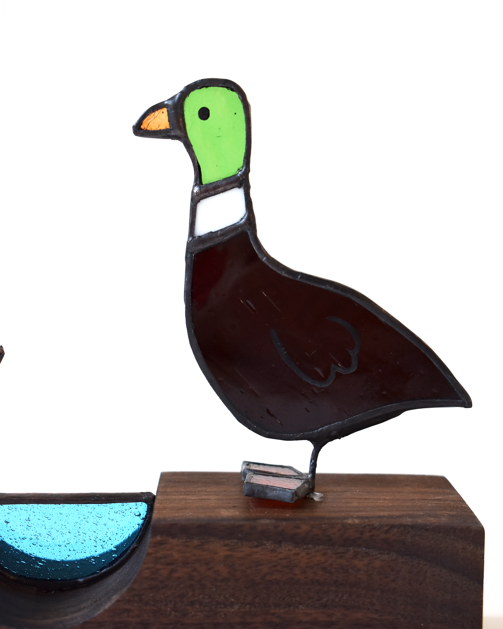 Decorative glass goose figure on a wooden base with a white background