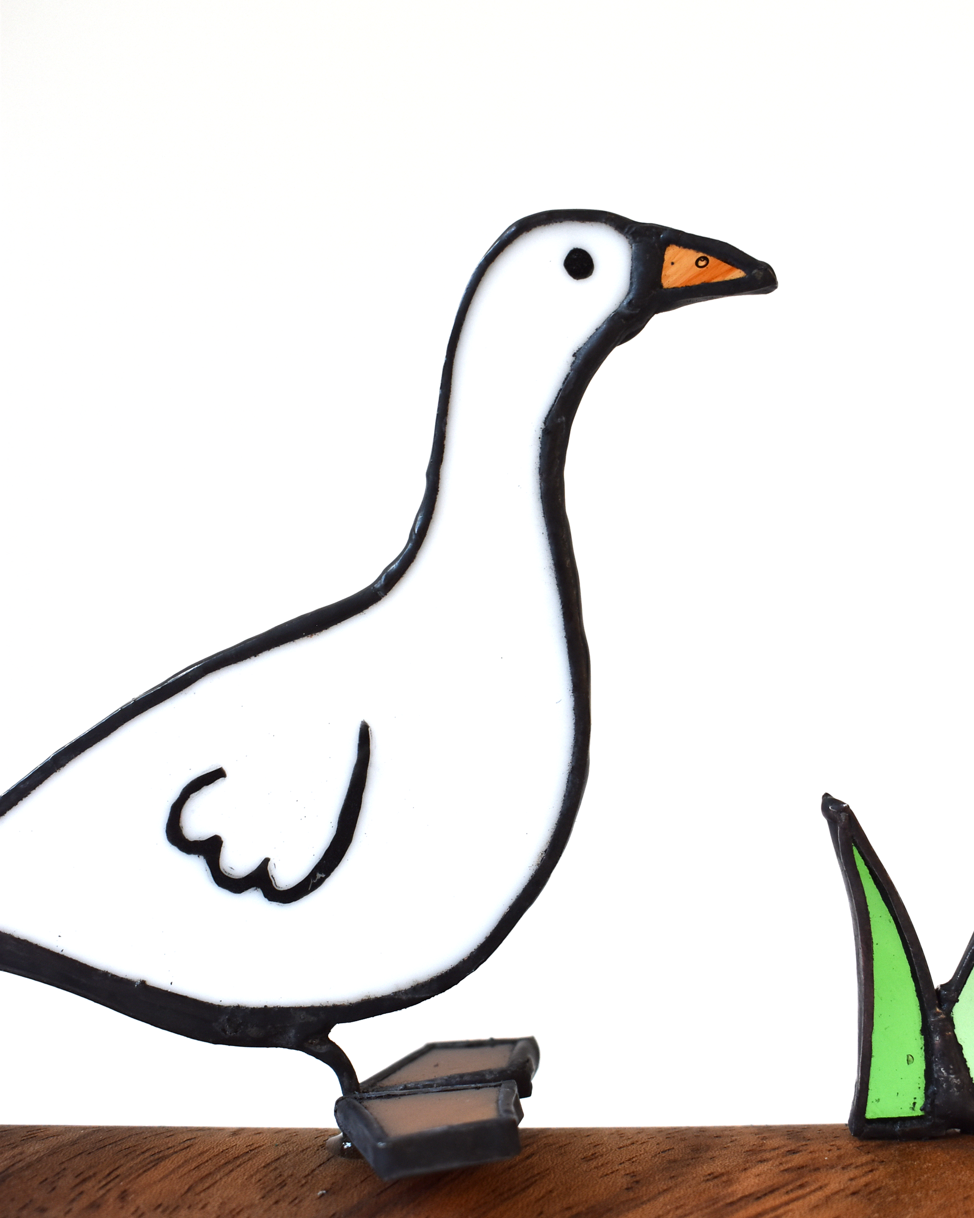 Decorative metal goose sculpture on a wooden surface with a white background