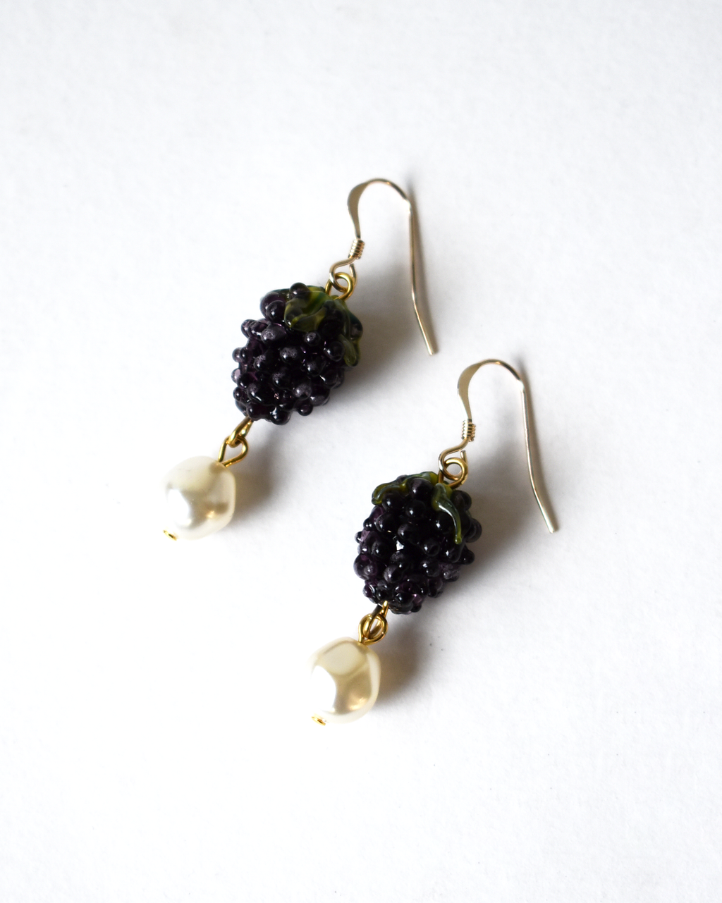 Pair of earrings with black berries and gold hooks on a white background