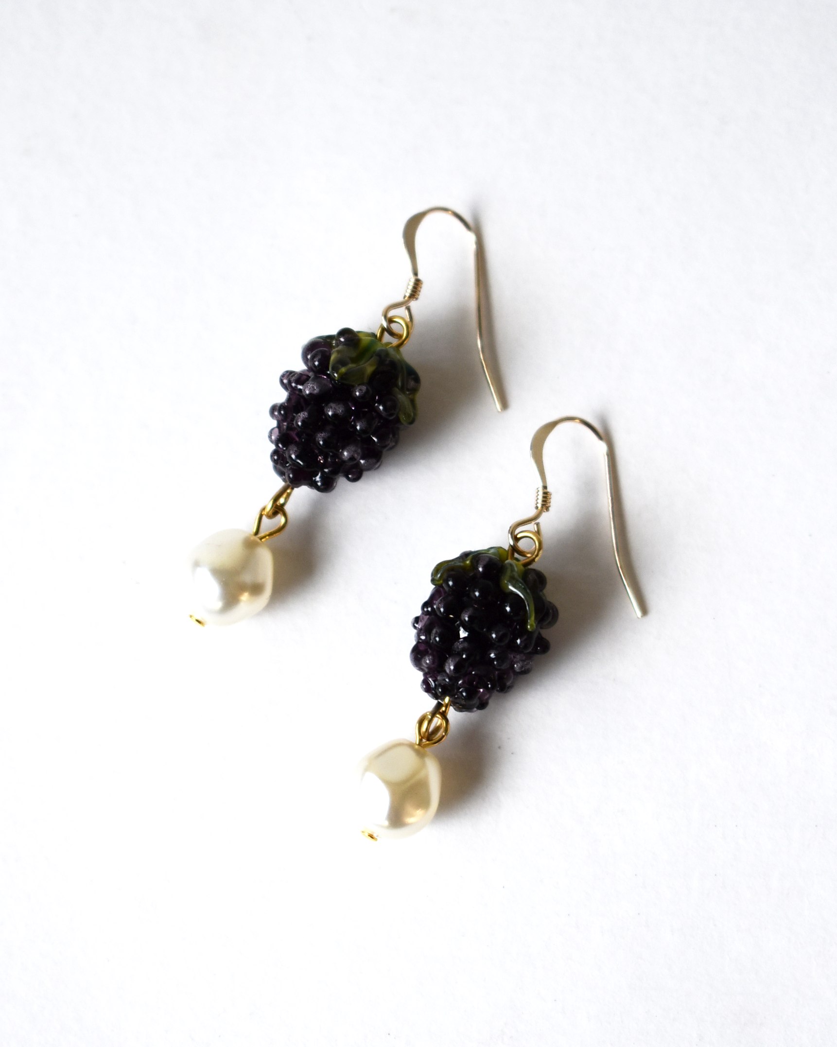 Pair of earrings with black berries and gold hooks on a white background