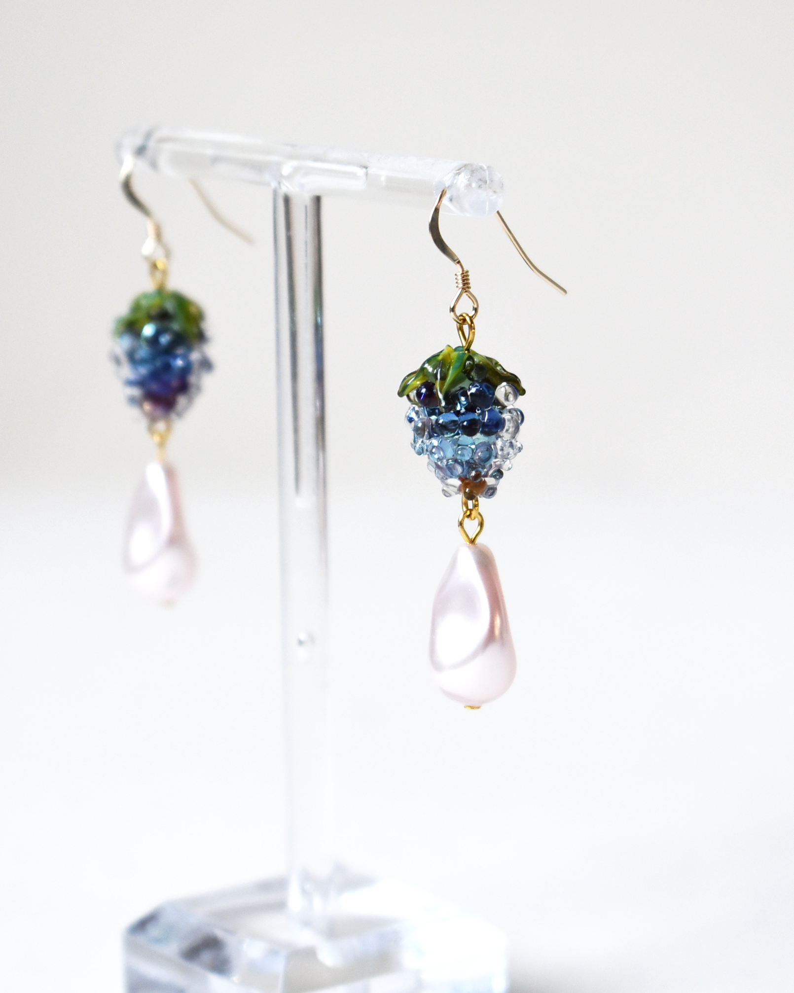 Pair of earrings on a clear stand with a white background