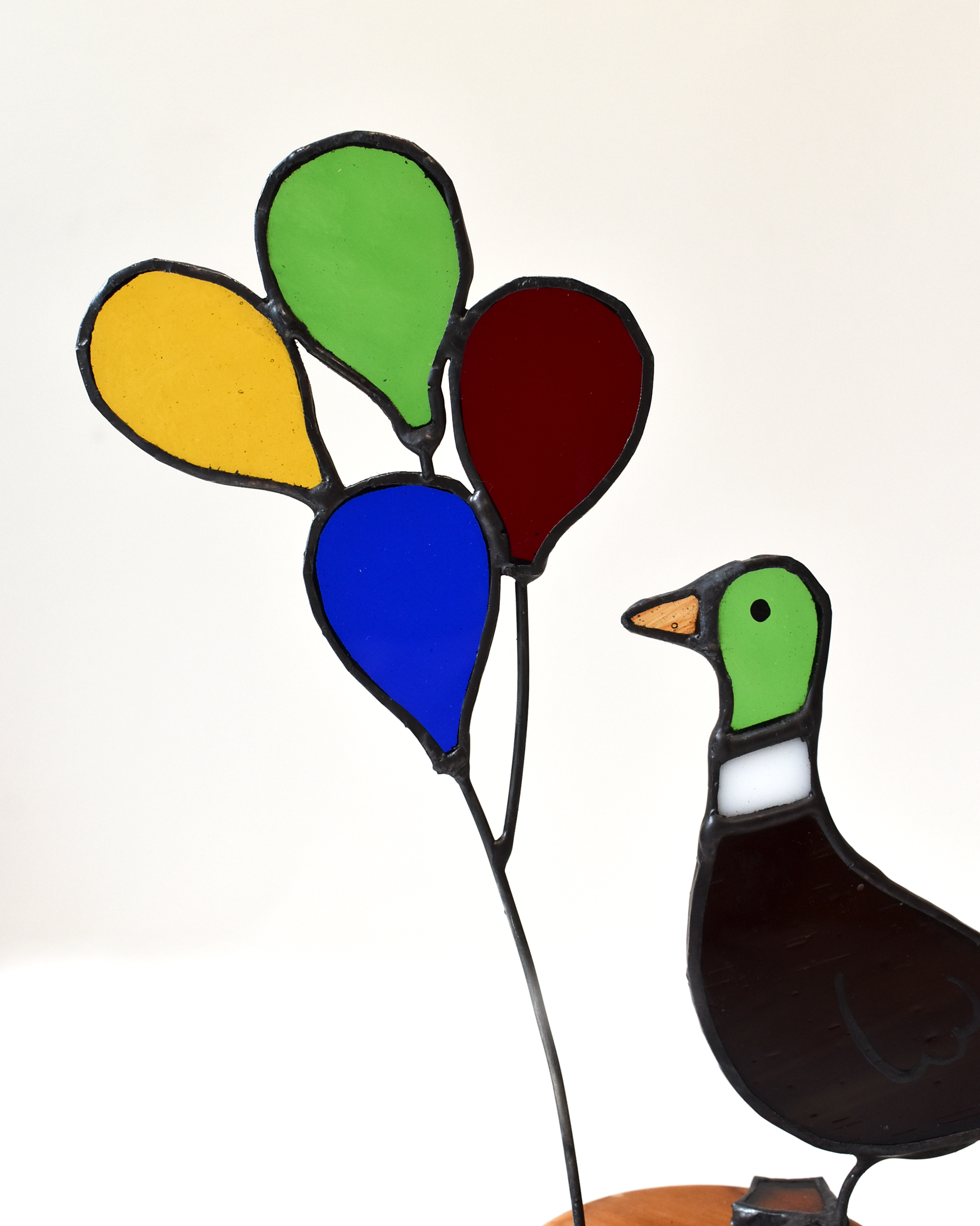 Decorative stained glass duck with colorful balloons on a white background