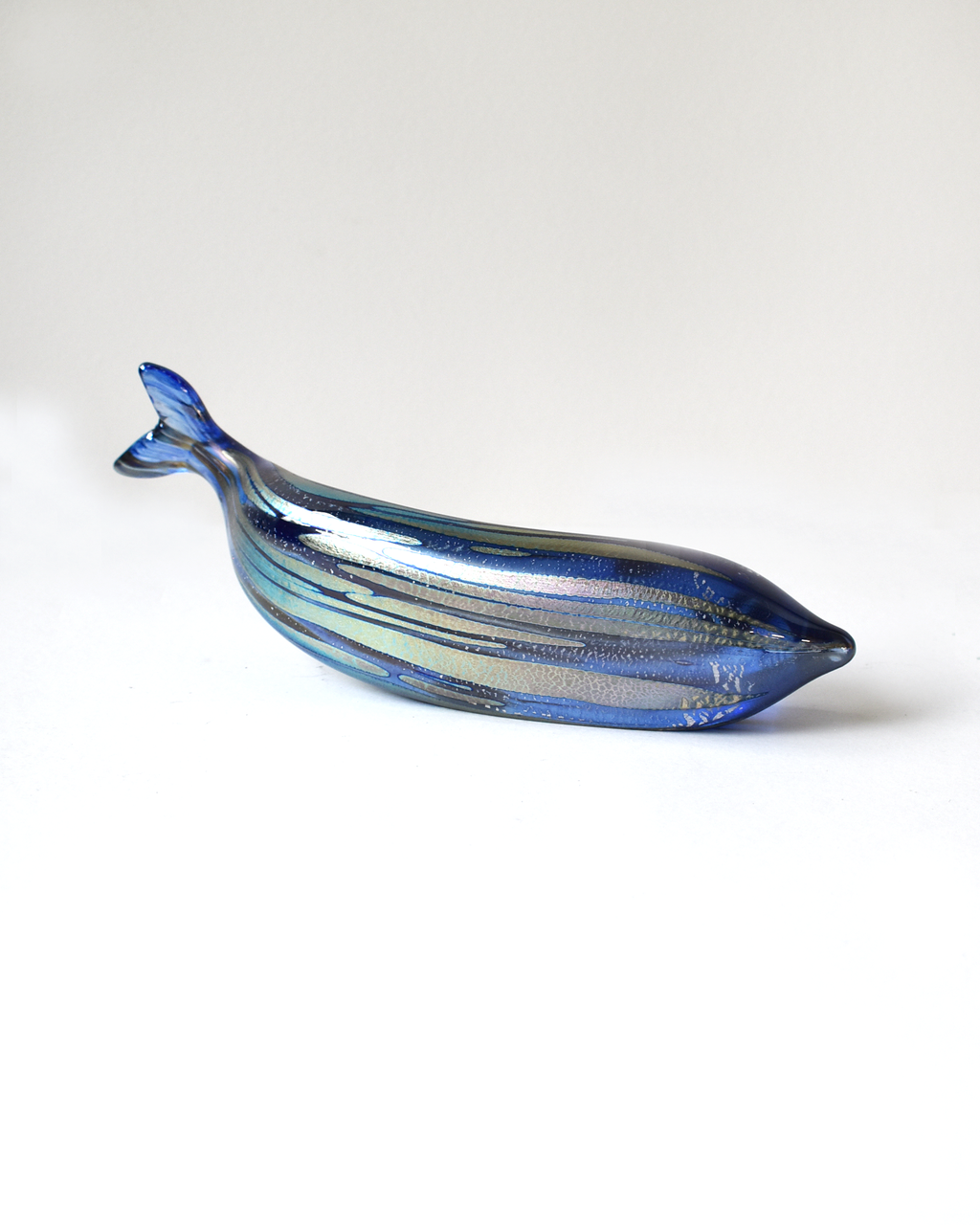 Blue glass whale-shaped object on a white background