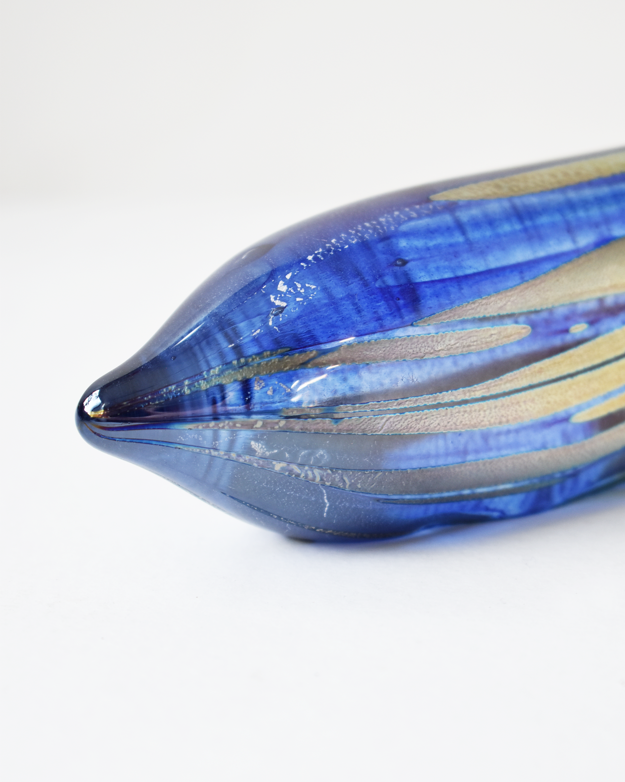Blue glass object with gold streaks on a white background