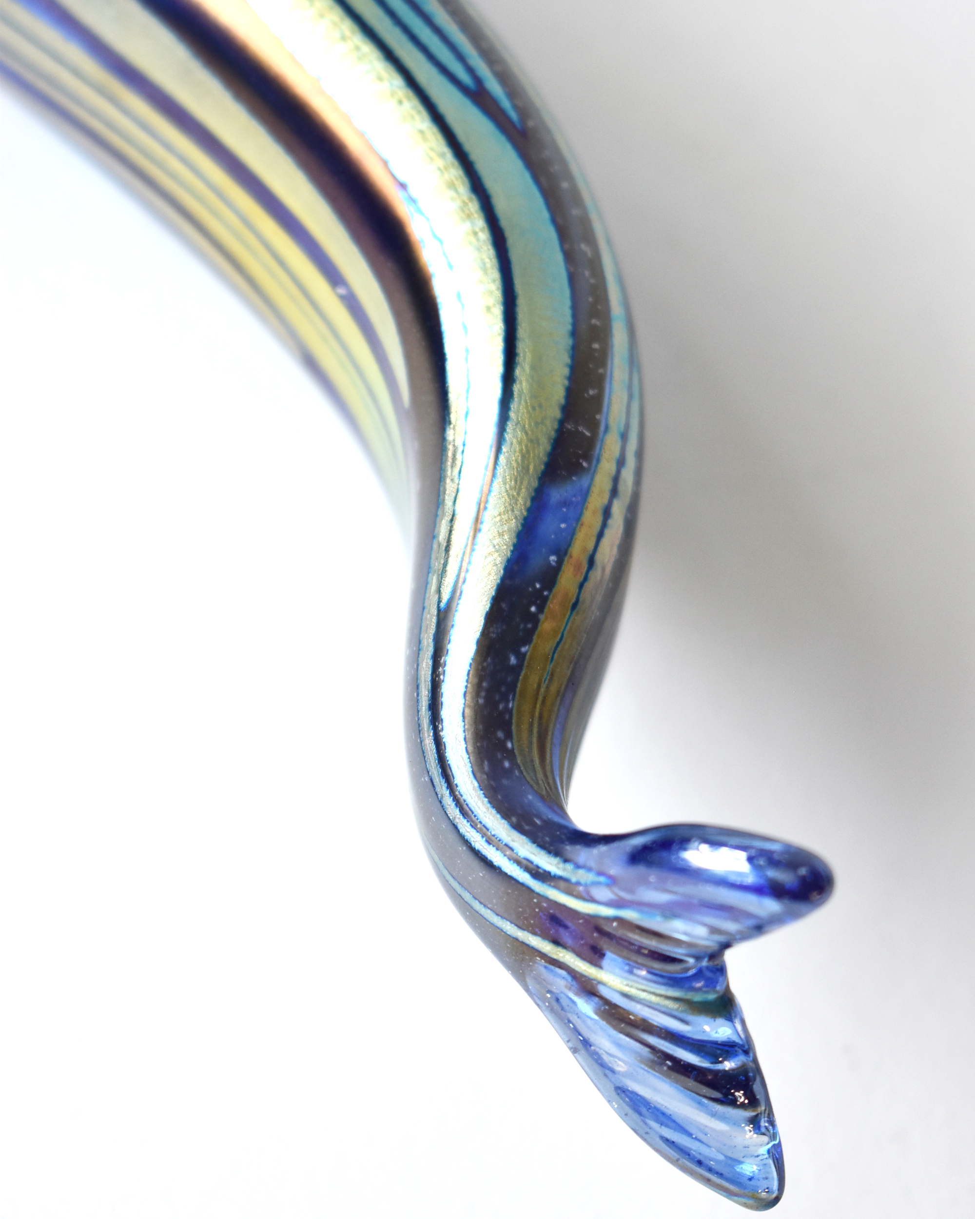 Glass sculpture with blue and green swirls on a white background