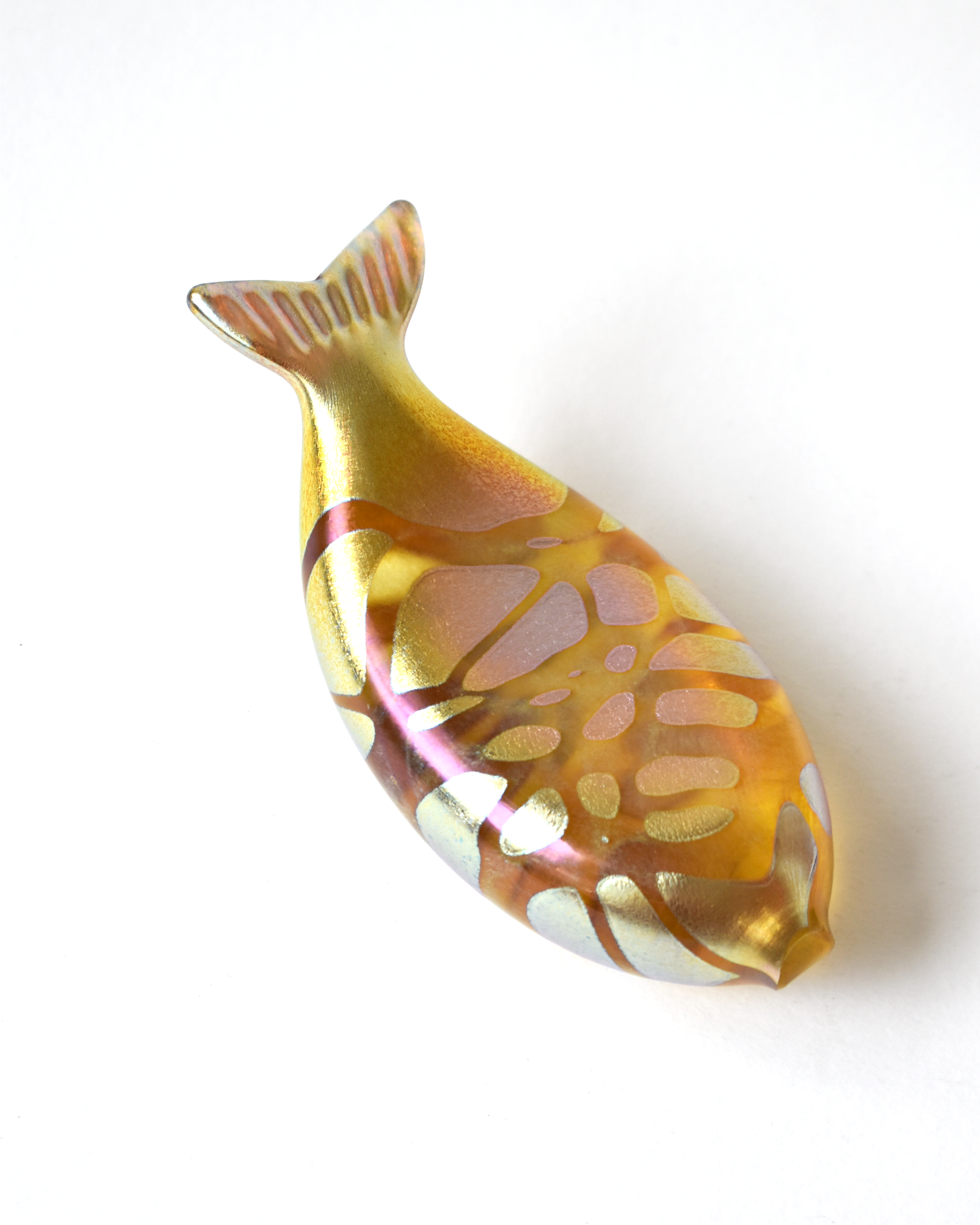 Decorative fish-shaped object with a gold and pink pattern on a white background