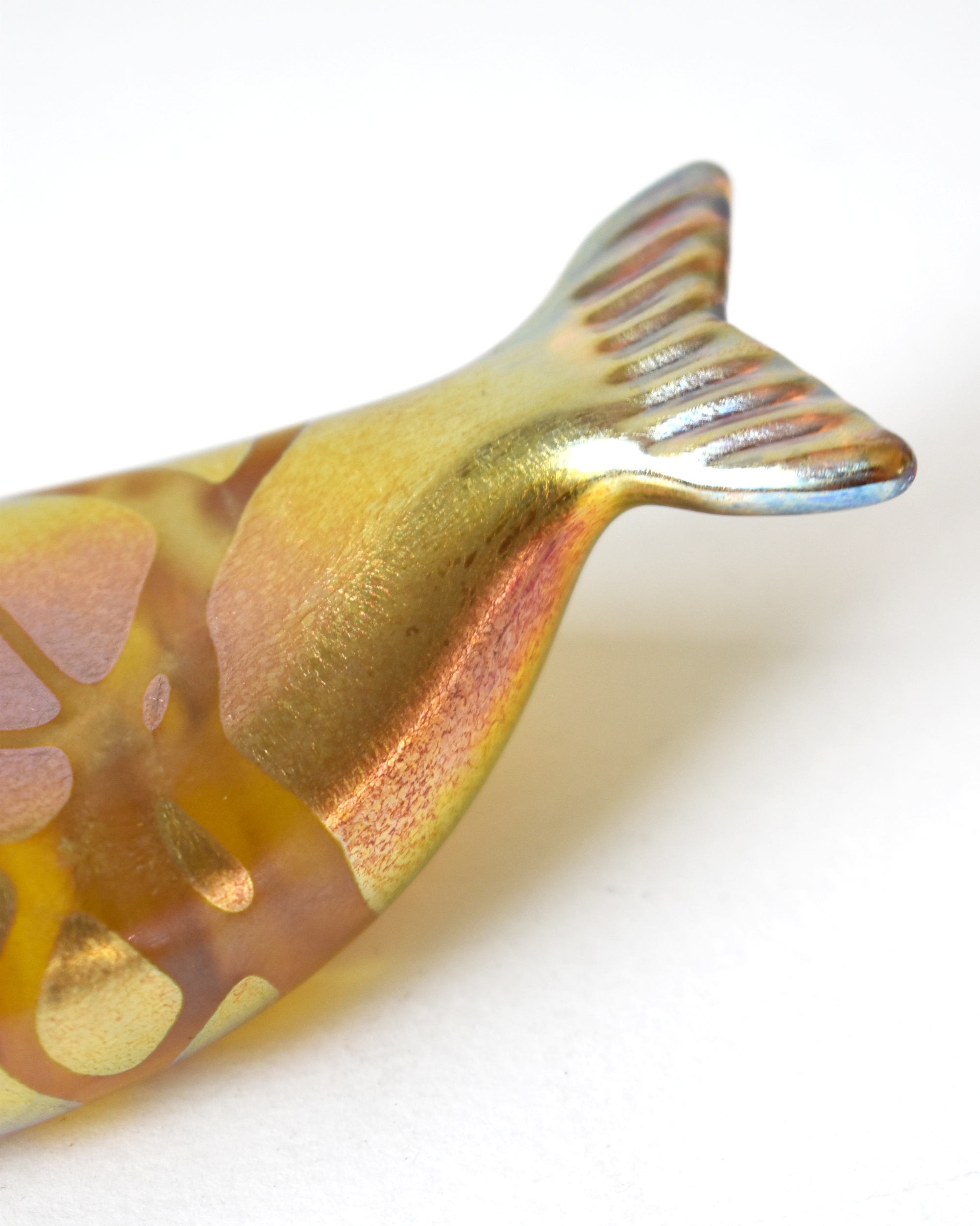 Close-up of a gold and copper fish-shaped object on a white background