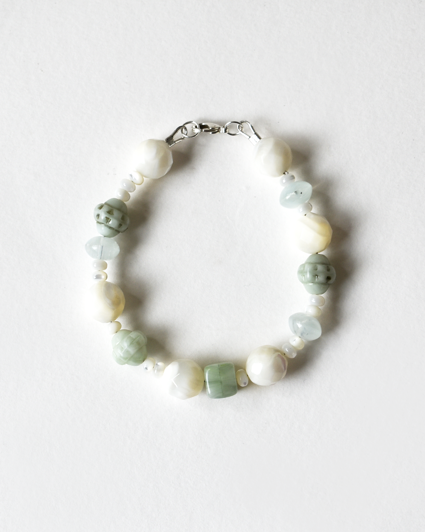 Bracelet with green and white beads on a light gray background