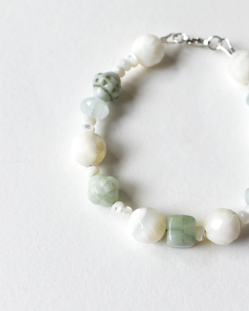 Bracelet with green and white beads on a light background