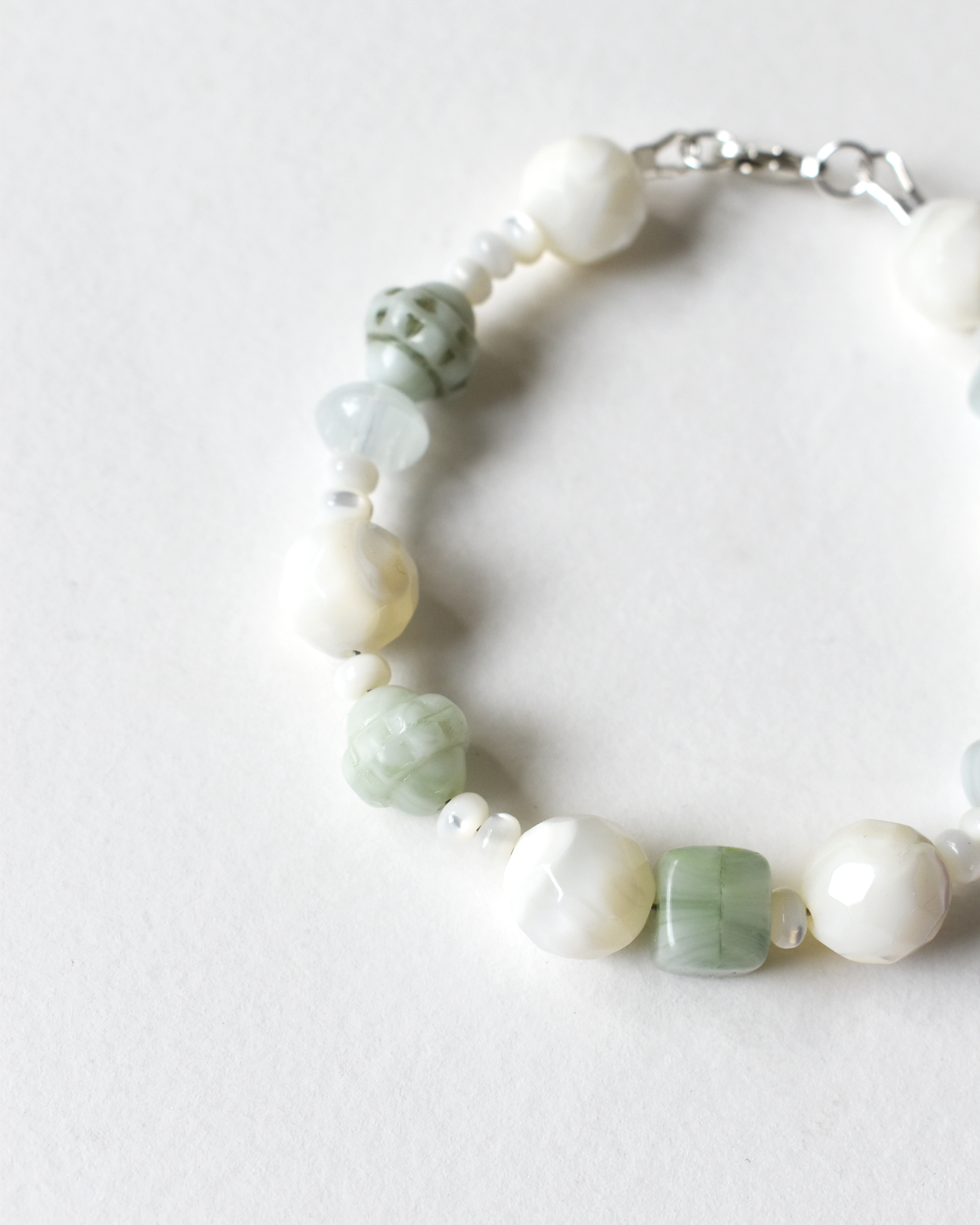 Bracelet with green and white beads on a light background