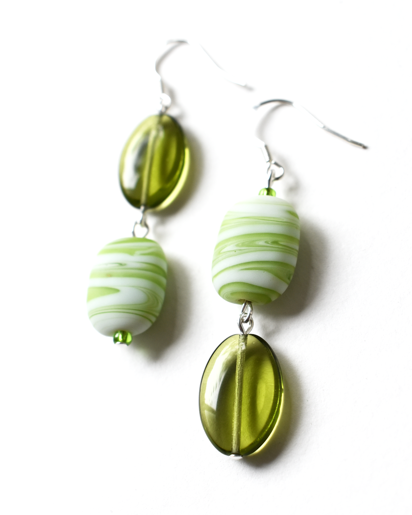 Green and white beaded earrings on a white background