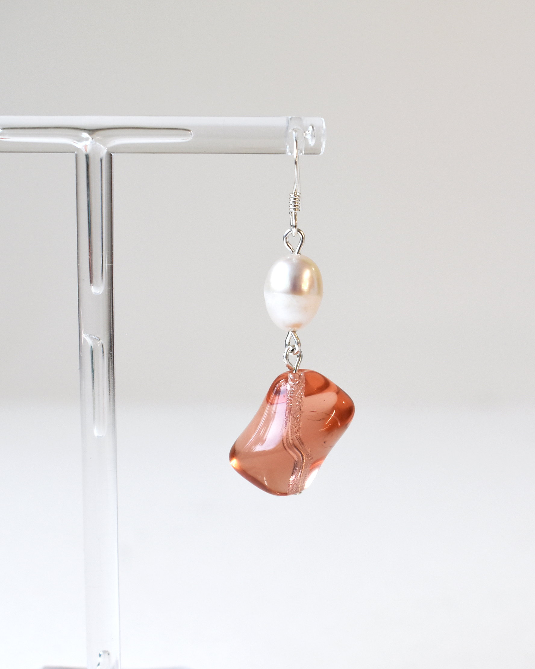 Earring with a large pink stone and pearl on a white background