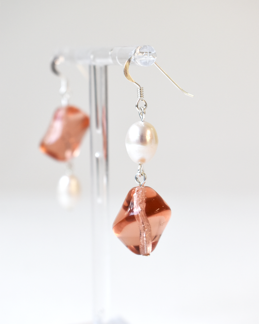 Pair of earrings with pink and white beads on a light gray background