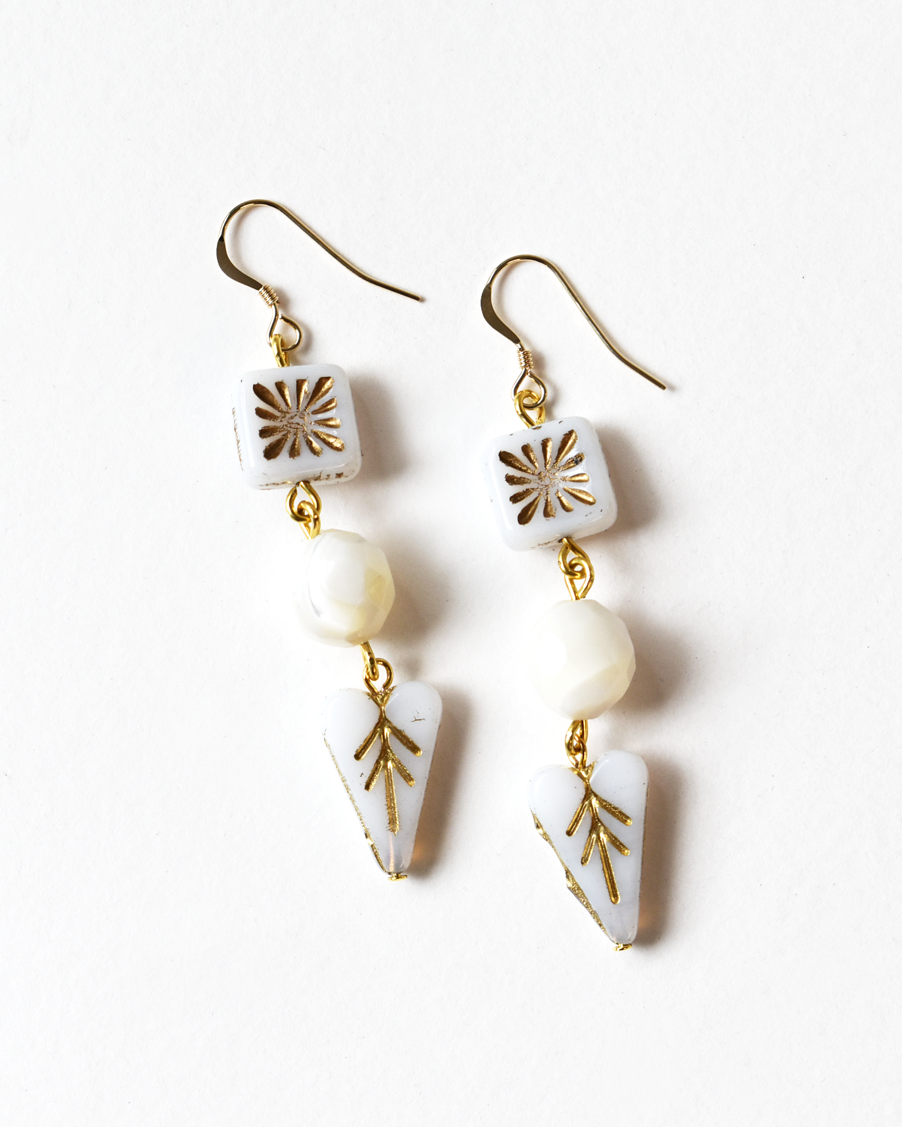 Pair of earrings with white and gold geometric designs on a white background