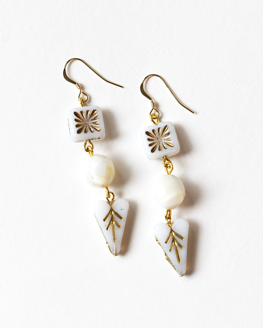 Pair of earrings with white and gold geometric designs on a white background